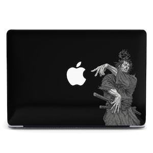 May include: Black laptop with a white Apple logo and a detailed illustration of a samurai warrior. The samurai is depicted in a dynamic pose, with a sword and traditional attire.