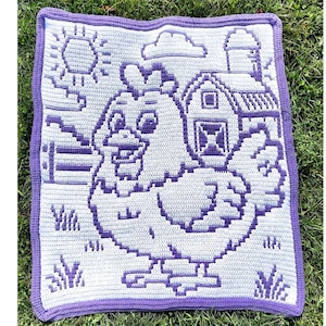 May include: A crocheted square blanket featuring a farm scene. The design includes a large chicken, a barn, a sun, and clouds, all in shades of white and purple. The blanket is bordered with a solid purple edge and is displayed on green grass.