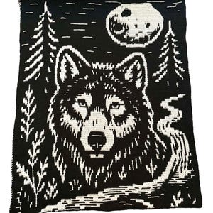 Puede incluir: Manta de ganchillo en blanco y negro con un lobo, árboles y una luna llena. La cara del lobo está centrada, con detalles de pelaje y ojos. Los árboles están a la izquierda y a la derecha, y la luna está en la esquina superior derecha.