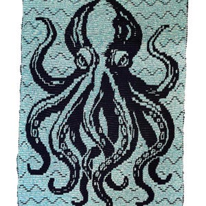 May include: A rectangular woven textile featuring a large, dark navy blue octopus graphic centered against a light teal background. The background is decorated with a repeating horizontal wavy line pattern, while the octopus displays detailed suckers.