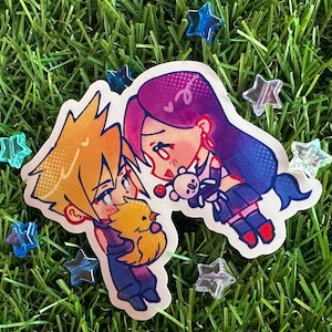 May include: A sticker featuring two anime-style characters, one with yellow hair holding a yellow chick, and the other with purple hair holding a teddy bear. The sticker is surrounded by star-shaped decorations on a green background.