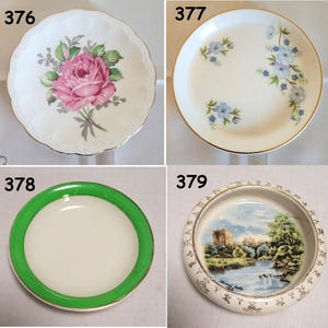 Peut inclure: Quatre assiettes décoratives en porcelaine vintage. Une assiette présente une rose rose, une autre des motifs floraux bleus, une troisième un bord vert et la dernière représente un paysage avec un château.
