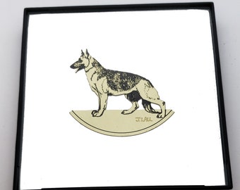 May include: A black and white illustration of a German Shepherd dog standing on a cream-colored crescent moon shape. The image is framed in a black frame and the artist's signature "J. LAUL" is visible in the bottom center of the image.