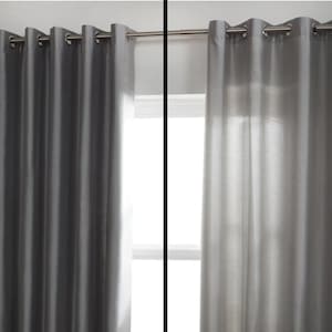 May include: Two identical curtains, one with a blackout lining and one without. The curtain with the blackout lining is dark gray and blocks out all light. The curtain without the blackout lining is light gray and allows light to shine through.
