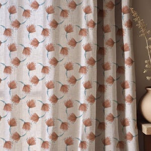 Puede incluir: Cortinas con un patrón floral repetido. Las flores son de un color marrón anaranjado cálido, con tallos azul claro, sobre un fondo neutro blanquecino. La tela tiene una apariencia texturizada.