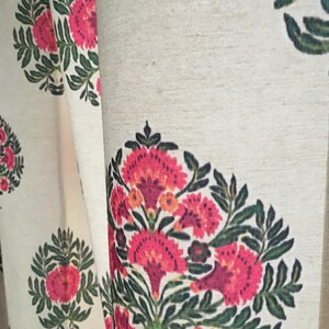 May include: White fabric with a repeating pattern of pink and green floral designs. The flowers are stylized and have a vintage look.