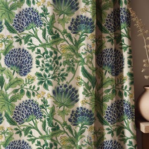 Op de afbeelding: Gordijnpaneel met een herhalend bloemmotief. Het ontwerp toont grote blauwe en groene bloemen, groene bladeren en gele accenten tegen een crèmekleurige achtergrond. De stof creëert een samenhangend patroon.