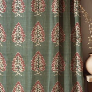Könnte beinhalten: Vorhangpaneel in Salbeigrün mit einem sich wiederholenden Muster stilisierter Bäume. Jeder Baum hat einen weißen Stamm, rote Blätter und grüne Äste. Der Stoff hat ein subtiles, strukturiertes Aussehen und verleiht dem Design Tiefe.