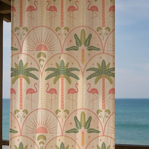 Könnte beinhalten: Beigefarbener Vorhang mit einem sich wiederholenden Muster aus rosa Flamingos, grünen Palmen und einem rosa Sonnendesign. Der Vorhang hängt vor einem Fenster mit Blick auf das Meer und den blauen Himmel.