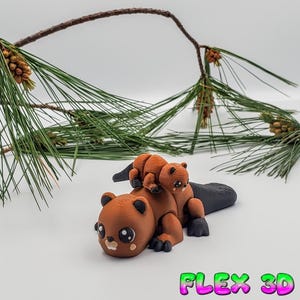 May include: A brown 3D-printed beaver figurine with a smaller beaver riding on its back. The figurine has large eyes and a black tail. The text "FLEX 3D" is in the bottom right corner.