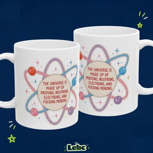 May include: Two white ceramic mugs featuring a central atom graphic with orbiting spheres in red, blue, and purple. The text reads: The universe is made up of protons, neutrons, electrons, and fucking morons. Small colorful stars surround the atom.