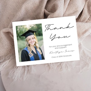 May include: A white graduation thank you card with a photo of a smiling graduate in a cap and gown. The card features the words "Thank You" in elegant script, along with a personalized message and the graduate's name.