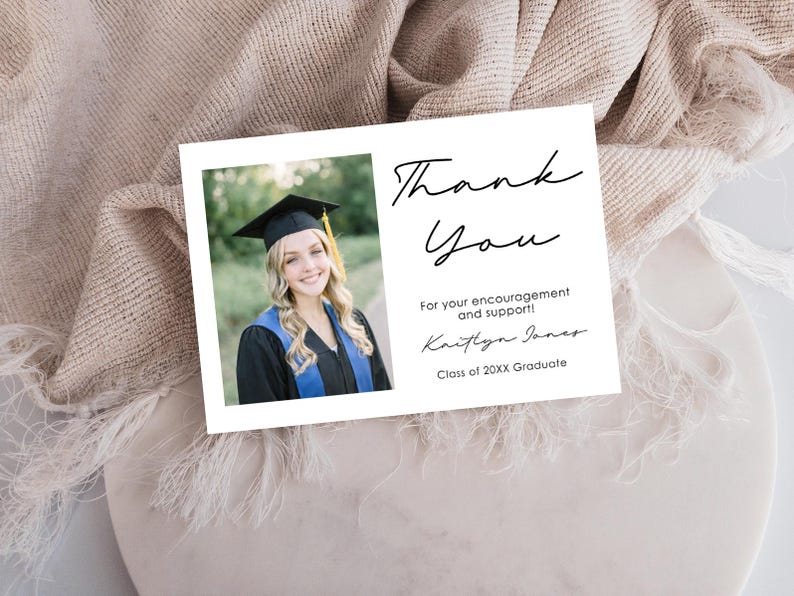 May include: A white graduation thank you card with a photo of a smiling graduate in a cap and gown. The card features the words "Thank You" in elegant script, along with a personalized message and the graduate's name.