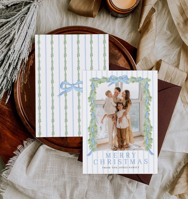 May include: Christmas card with a family photo, featuring a blue and white striped design with a watercolor garland and bow. The text reads "Merry Christmas from The Jones Family."