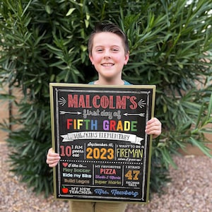 a young boy holding up a sign for a fifth grade class