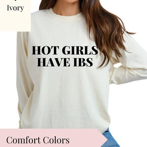 May include: A long-sleeved, ivory-colored sweatshirt with the text "HOT GIRLS HAVE IBS" printed in black.