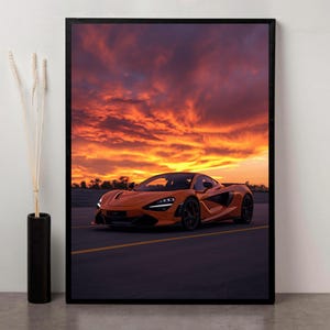 Peut inclure: Impression encadrée d'une voiture de sport orange sur fond de coucher de soleil flamboyant. La voiture est sur une route sombre avec des lignes jaunes, le ciel est orange, rouge et violet.