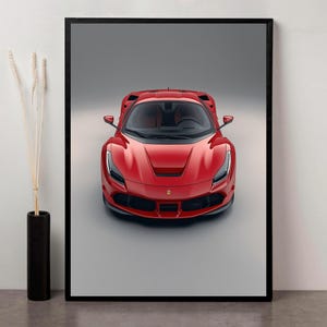 Puede incluir: Impresión enmarcada de un coche deportivo rojo. El coche se ve de frente, mostrando su diseño elegante y sus características aerodinámicas. El coche tiene un perfil bajo, con una prominente parrilla delantera y faros. El interior es visible a través del parabrisas.