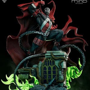 May include: A detailed Spawn action figure statue featuring a black and red costume with a flowing red cape, standing on a stone base with a gothic window and green flames. The figure holds a long black chain, with Poly Mind Studio text visible.