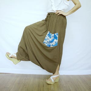 May include: A brown, flowing skirt with a blue and white patterned pocket. The skirt is worn with a white top and white sandals.