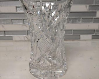 May include: A clear glass vase with a cut glass design. The vase has a wide mouth and a narrow base.