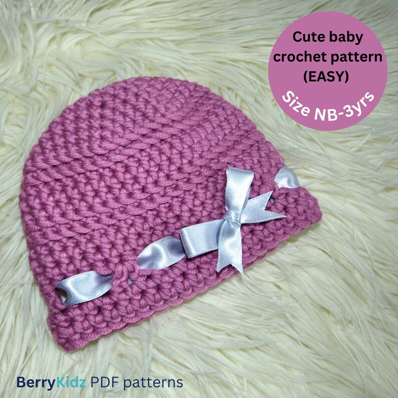May include: A pink crocheted baby hat with a white satin bow. The hat is on a white fluffy surface. The text "Cute baby crochet pattern (EASY) Size NB-3yrs" is in the upper right corner of the image.