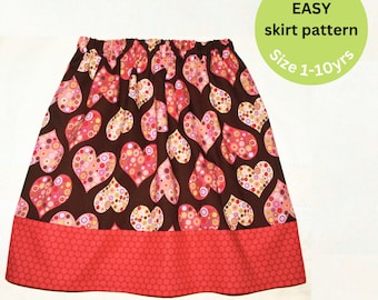 May include: A brown skirt with a pink and white heart pattern and a red polka dot trim. The skirt is for girls and has a size range of 1-10 years. The text on the image reads "Super EASY skirt pattern Size 1-10yrs".