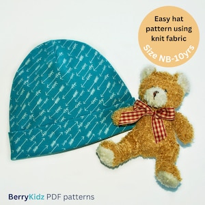 May include: A teal blue knit hat with a white arrow pattern. The hat is on a white surface next to a brown teddy bear with a red and white checkered bow. The text "Easy hat pattern using knit fabric Size NB-10yrs" is in a yellow circle.