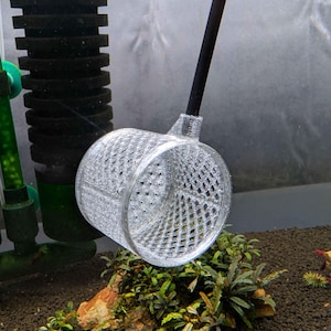 May include: A clear, cylindrical, 3D-printed plastic net with a diamond-patterned mesh structure attached to a thin, straight black handle, designed for use in an aquarium environment to capture small aquatic life or debris.