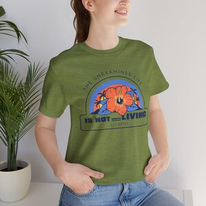 May include: Green t-shirt with a graphic print of a hibiscus flower and the text "The unexamined life is not worth living - Socrates".