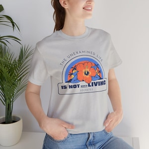 May include: Gray t-shirt with a graphic print of a hibiscus flower and the text "The unexamined life is not worth living - Socrates".