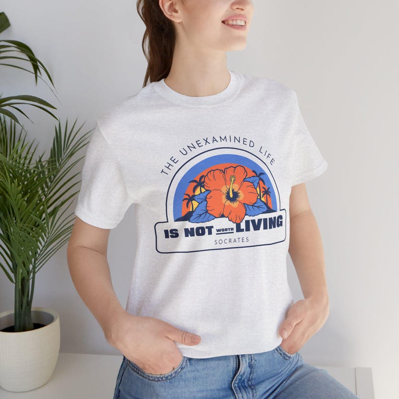 May include: A white t-shirt with a graphic print of a tropical flower and the text "The unexamined life is not worth living - Socrates".