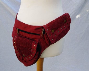 May include: A burgundy canvas belt with multiple pockets and decorative metal studs. The belt has a zippered pocket on the front and a flap pocket on the side.