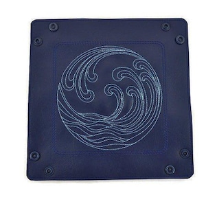 May include: A dark blue leather tray with a stitched wave design in a lighter blue color. The tray has four metal rivets on the edges.
