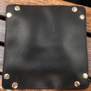 May include: A black leather tray with silver metal rivets around the edges.