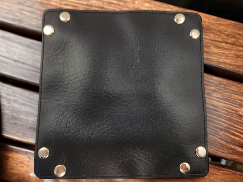 May include: A black leather tray with silver metal rivets around the edges.