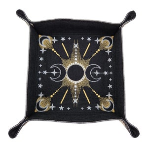 May include: A black felt dice tray with a gold and silver embroidered design of moons and stars.