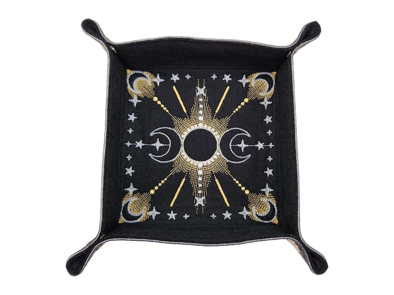 May include: A black felt dice tray with a gold and silver embroidered design of moons and stars.
