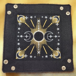 May include: Black felt tray with silver and gold embroidery of a sun and moon design. The tray has silver metal rivets around the edges.