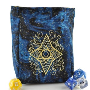 May include: A blue dice bag with a gold embroidered star design. The bag is made of a fabric with a galaxy print. The bag is filled with dice.