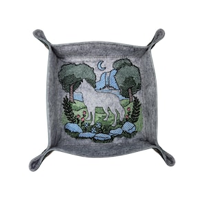 May include: A square gray felt valet tray with snap corners featuring an embroidered scene of a white wolf standing in a landscape with green trees, blue rocks, pink flowers, and a crescent moon in the sky above a blue waterfall and stream.