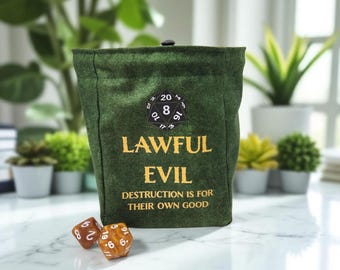 May include: A dark green dice bag with the words "LAWFUL EVIL" in gold lettering. The bag has a black and white D20 patch and the phrase "DESTRUCTION IS FOR THEIR OWN GOOD". Two dice are in front of the bag.