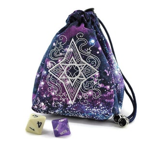 May include: A purple and blue dice bag with a white star design and a galaxy print. The bag is made of fabric and has a drawstring closure. There are three dice on the table next to the bag.