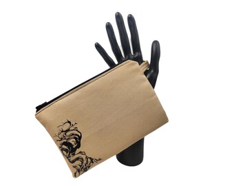 Può includere: Un astuccio in tela beige con cerniera nera e un disegno di albero astratto nero sul davanti. L'astuccio è tenuto da una mano di manichino nera su sfondo bianco. L'astuccio è rettangolare.