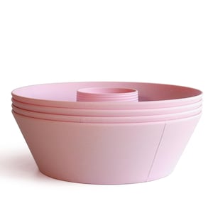 May include: A stack of light pink, circular baking tins with a central tube. Each tin features a smooth, tapered exterior wall and a raised, cylindrical centre piece designed for ring-shaped cakes, presented in a clean, uniform pastel colour.