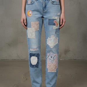 May include: Light blue denim jeans with various fabric patches. Patches include floral, paisley, and solid designs. The jeans have distressed details and a classic five-pocket design.