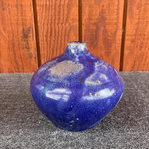 May include: A small, round, blue ceramic vase with a speckled glaze.