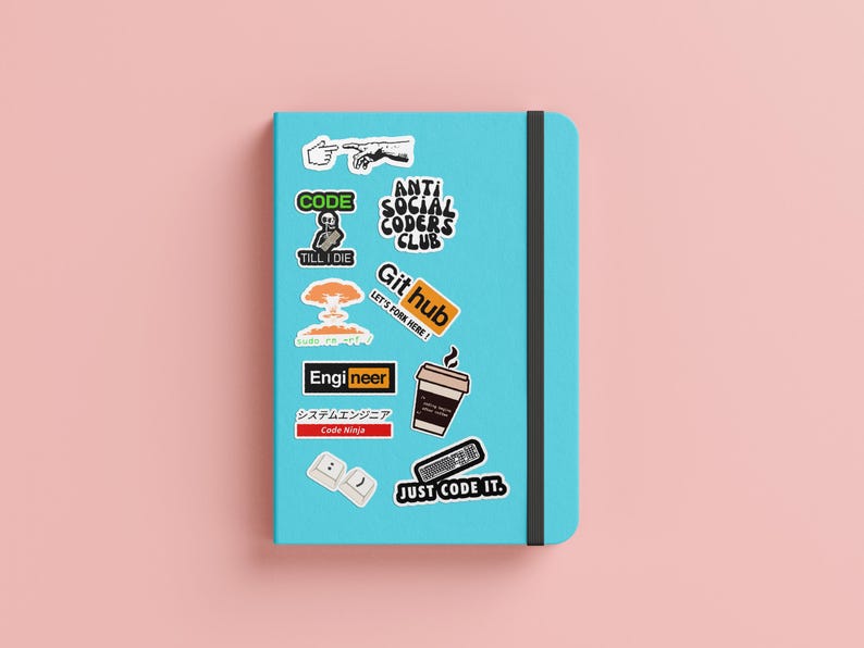May include: A blue notebook with various stickers on it. The stickers feature text like "Code", "Anti Social Coders Club", "Git Hub", "Engineer", and "Just Code It".