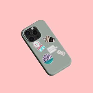 May include: A green phone case with various stickers, including a coffee cup, a keyboard, and a sticker that says "Coding Life".
