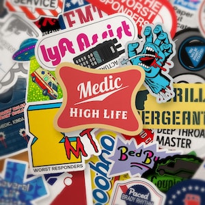 Puede incluir: Una colección de pegatinas coloridas con varios diseños y texto. Las pegatinas notables incluyen un logotipo rojo y dorado de "Medic High Life", una mano azul con una boca sangrienta y una pegatina de "Worst Responders". Otras pegatinas presentan texto como "Lyft Assist" y "Grill".